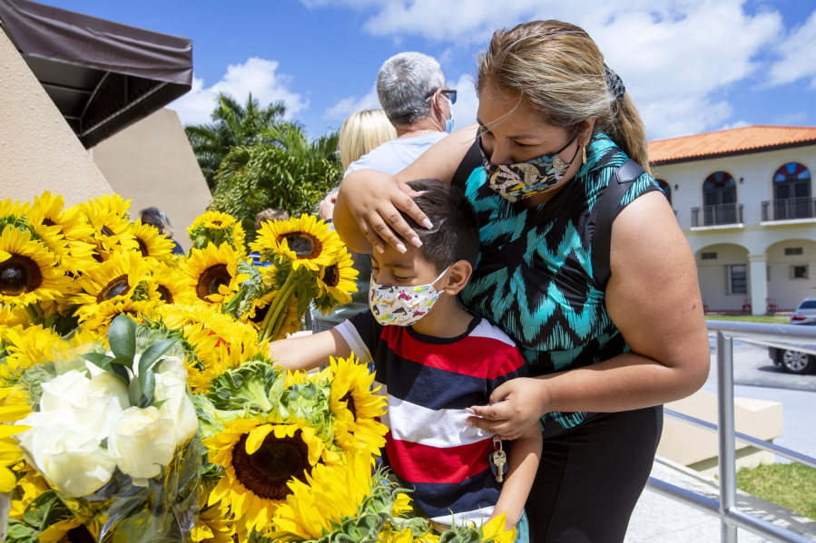 Janet Hidalgo, 34 and her son, Gustavo Galindo, 5, drops off a bouquet of sunflowers as they pay their respects to the church and those stuck overseas in Cuba, while groups advocating for the Cuban family reunification program to resume and the reopening of visa services in Havana hold a prayer at Ermita de la Caridad in Miami, Florida, on Sunday, Mar., 14, 2021. More than 78 thousand Cubans are waiting for an immigration visa to come to the United States, while another 22,000 remain in limbo after the suspension of a family reunification program. (Daniel A.