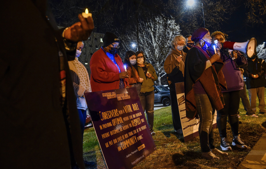 Health care workers from Research and Menorah medical centers hold a candlelight vigil to commemorate the one-year anniversary of the coronavirus pandemic and to honor those who died from COVID-19, as well as those who survived, on Thursday, March 11, 2021, outside of Research Medical Center. They bowed their heads during a prayer.