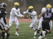 Evergreen's JJ Woodin (9) hands off to teammate O'Shay Jackson (6) in the first quarter at McKenzie Stadium on Friday afternoon, March 5, 2021.