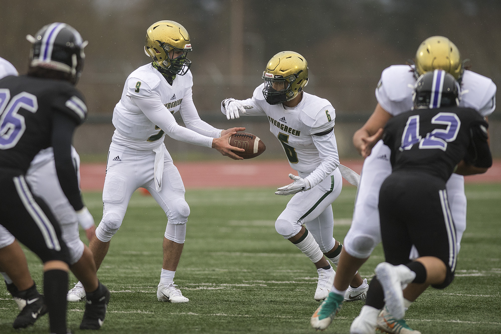 Evergreen's JJ Woodin (9) hands off to teammate O'Shay Jackson (6) in the first quarter at McKenzie Stadium on Friday afternoon, March 5, 2021.