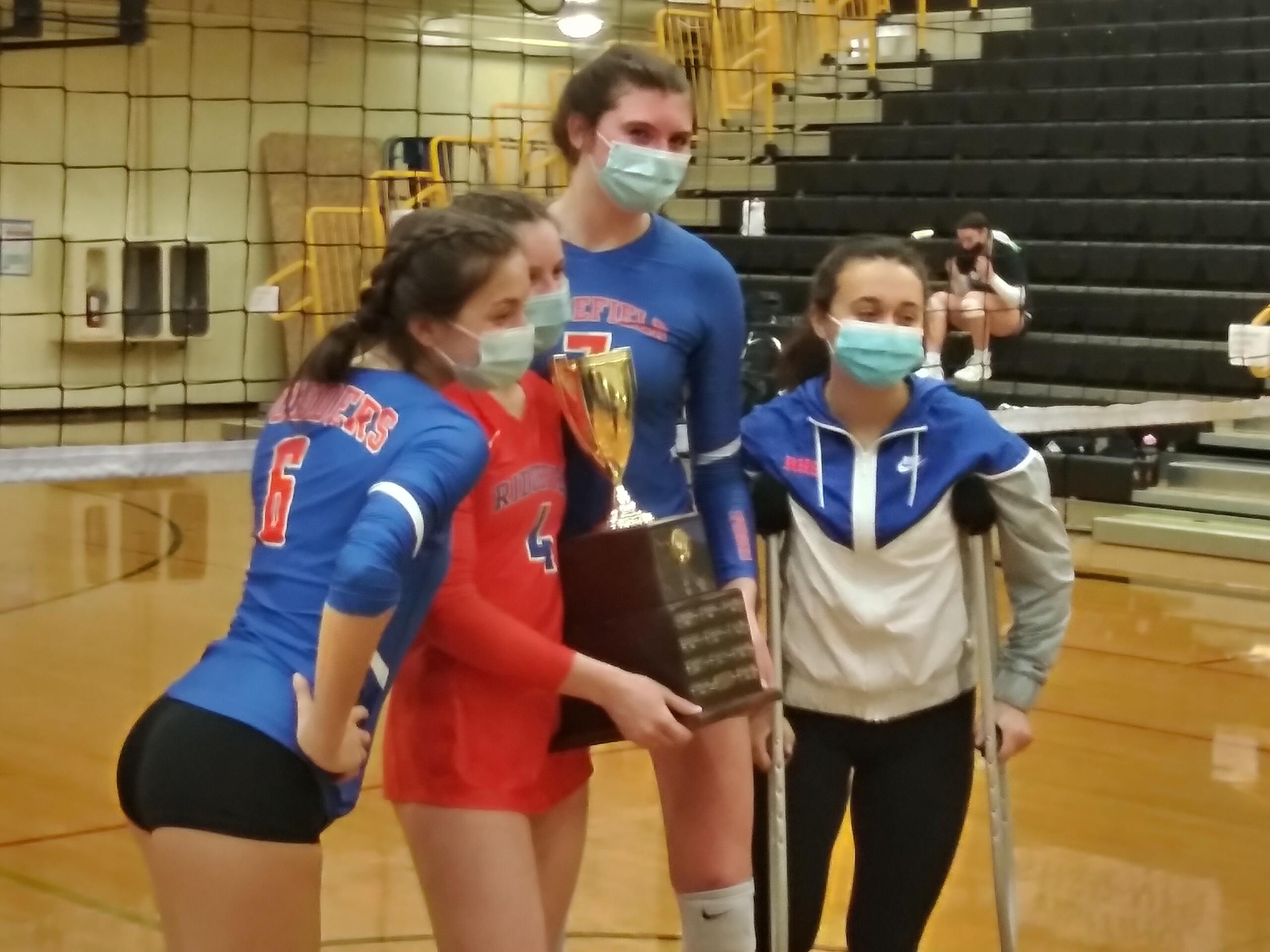 Ridgefield seniors (from left) Presley McCaskill, Emilea Stepaniuk, Allie Andrew and Kohana Fukuchi posed with the district trophy after Ridgefield beat Woodland for the 2A district volleyball title (Tim Martinez / The Columbian)