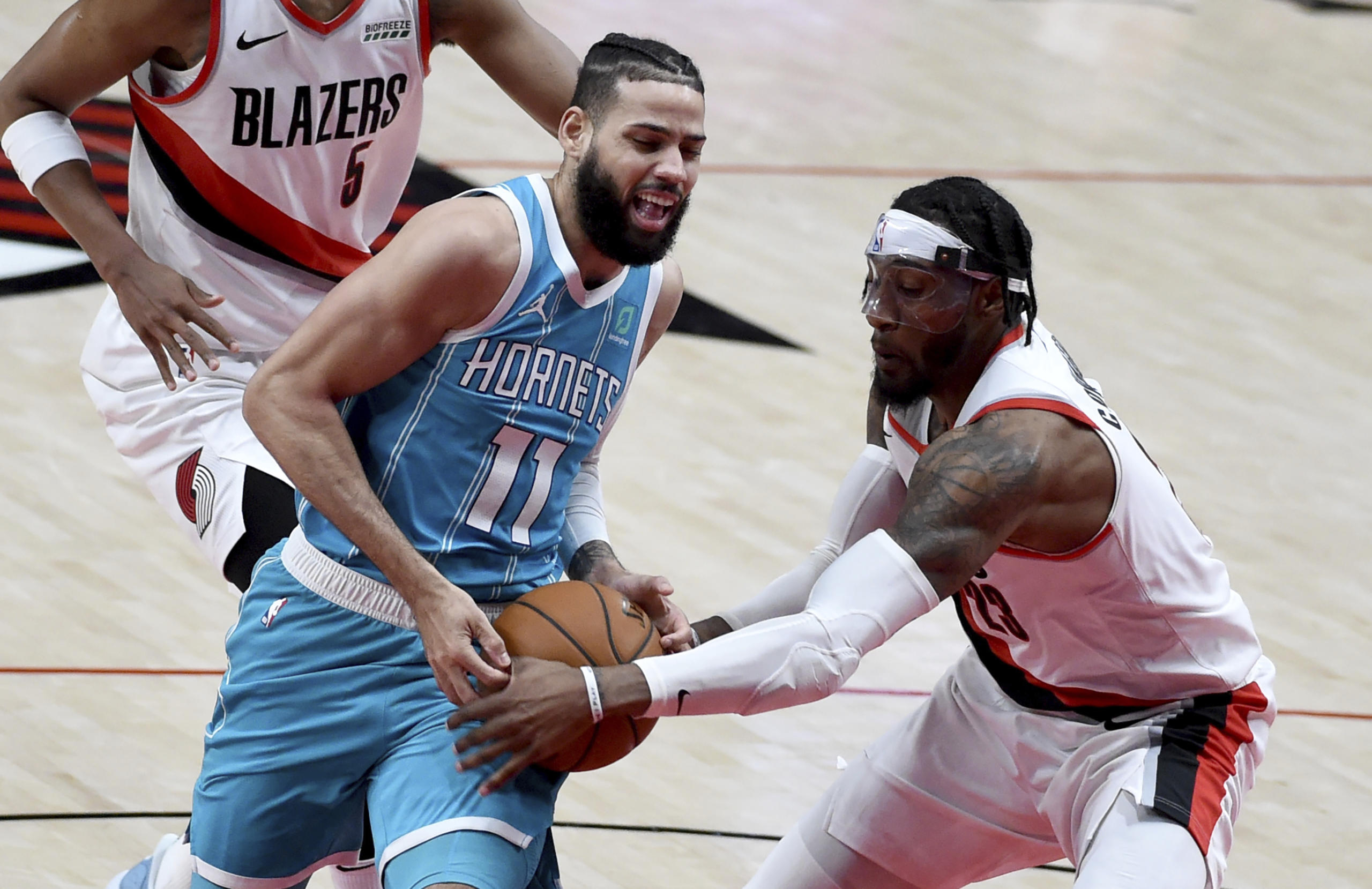 Portland Trail Blazers forward Robert Covington, right, grabs the ball away from Charlotte Hornets forward Cody Martin, left, during the first half of an NBA basketball game in Portland, Ore., Monday, March 1, 2021.