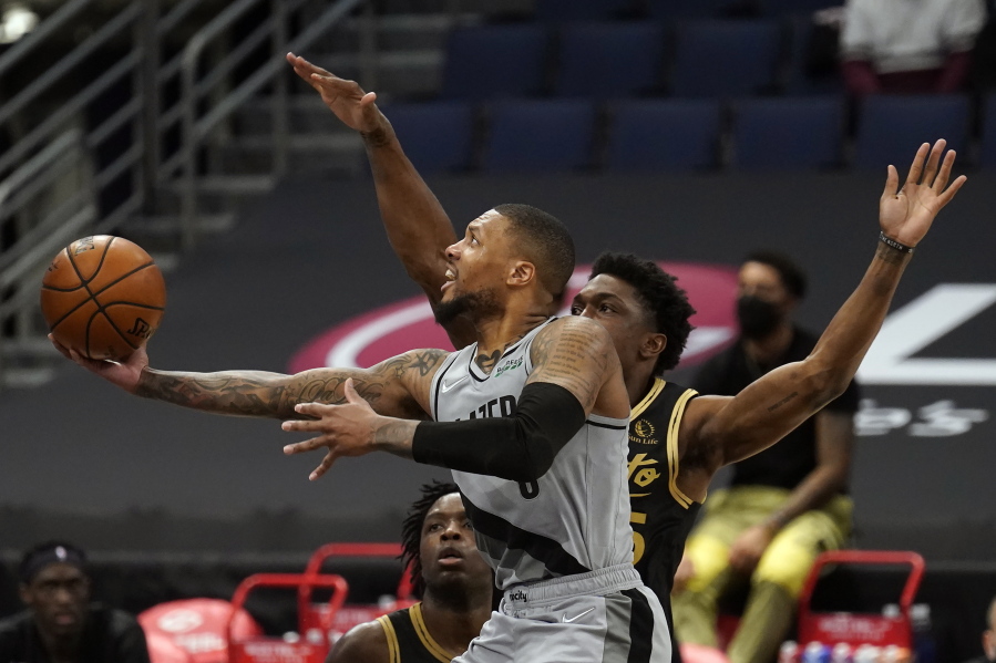 Portland Trail Blazers guard Damian Lillard (0) goes for a layup after getting around Toronto Raptors forward Stanley Johnson (5) during the second half of an NBA basketball game Sunday, March 28, 2021, in Tampa, Fla.