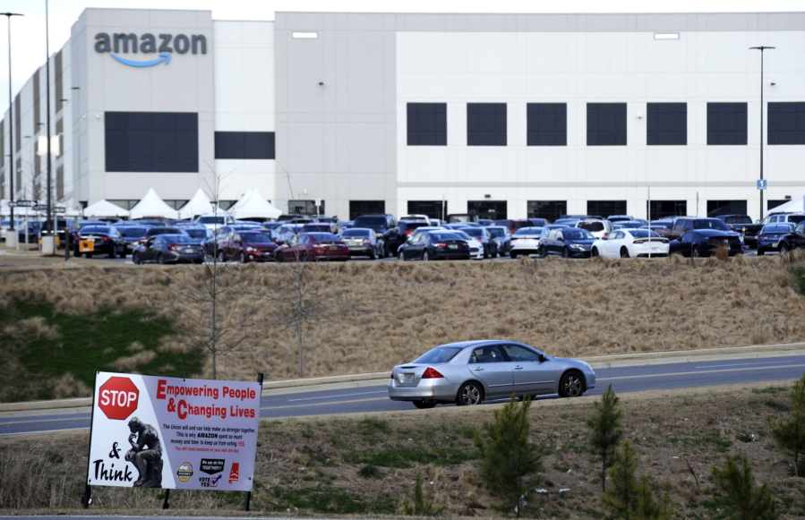 FILE- This Feb. 9, 2021 photo file photo,  a car enters an Amazon facility where labor is trying to organize workers in Bessemer, Ala.  Organizers are pushing for some 6,000 Amazon workers  to join the Retail, Wholesale and Department Store Union on the promise it will lead to better working conditions, better pay and more respect. Amazon is pushing back, arguing that it already offers more than twice the minimum wage in Alabama and workers get such benefits as health care, vision and dental insurance without paying union dues.