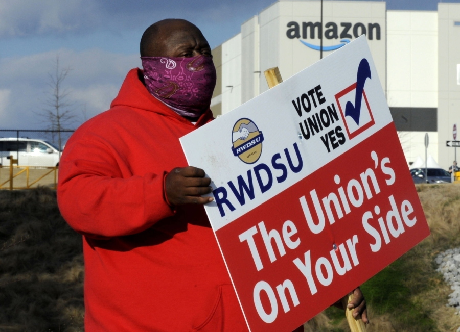 FILE - In this Tuesday, Feb. 9, 2021, file photo, Michael Foster of the Retail, Wholesale and Department Store Union holds a sign outside an Amazon facility where labor is trying to organize workers in Bessemer, Ala. Nearly 6,000 Amazon warehouse workers in Bessemer are deciding whether they want to form a union, the biggest labor push in the online shopping giant&#039;s history. Mail-in voting started in early February. Ballots must be received by the end of Monday March 29, 2021. The National Labor Relations Board starts counting votes the next day.