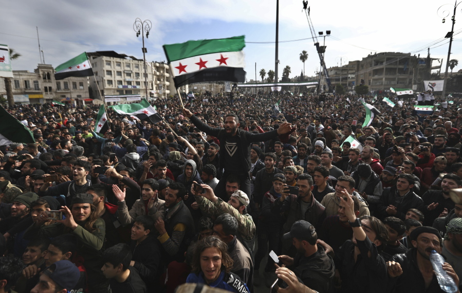 In this March 15, 2021, photo, thousands of anti-Syrian government protesters shout slogans and wave revolutionary flags, to mark 10 years since the start of a popular uprising against President Bashar Assad&#039;s rule, that later turned into an insurgency and civil war, in Idlib, the last major opposition-held area of the country, in northwest Syria. The Biden administration is mulling over America&#039;s role in Syria&#039;s ongoing conflict as the U.S. tries to break away from Middle East wars. But Vladimir Putin&#039;s top diplomat already has been busy on the ground, trying to win support for a Syria approach that could establish Russia as a broker of security and power in the region.