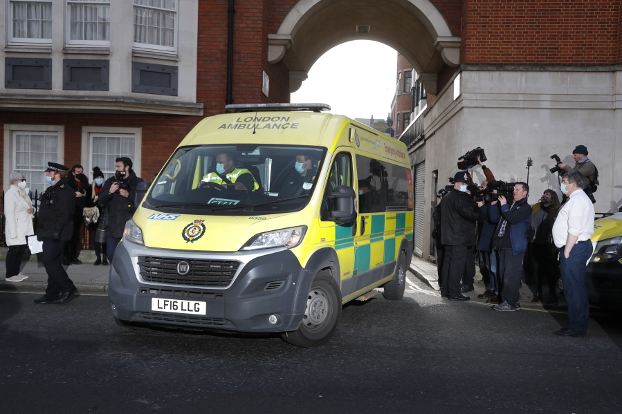 Police officers stand at an entrance to the King Edward VII Hospital where Prince Philip is being treated for an infection, as an ambulance is driven out, in London, Monday, March 1, 2021.