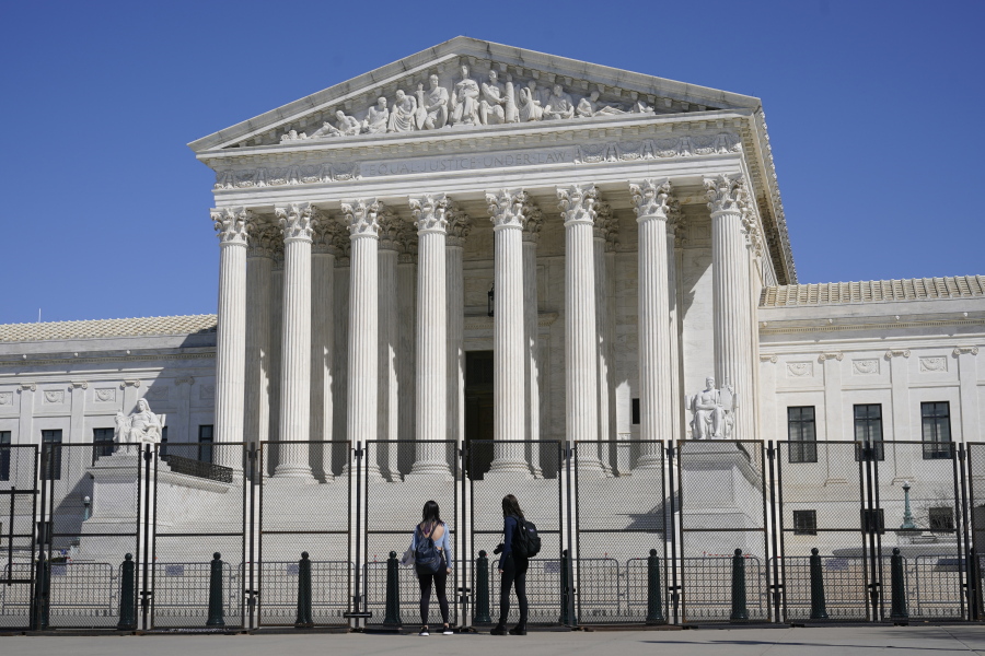 People view the Supreme Court building from behind security fencing on Capitol Hill in Washington, Sunday, March 21, 2021, after portions of an outer perimeter of fencing were removed overnight to allow public access.