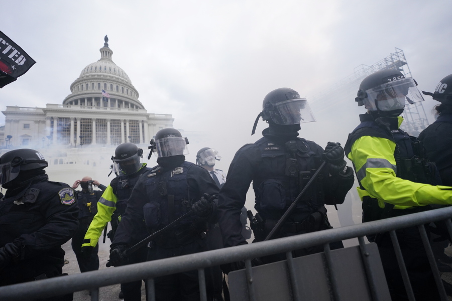 FILE - In this Jan. 6, 2021, file photo, police stand guard after holding off rioters who tried to break through a police barrier at the Capitol in Washington. Hundreds of emails, texts, photos and documents obtained by the Associated Press show how a patchwork of law enforcement agencies from all directions tried to give support as protesters poured into town.