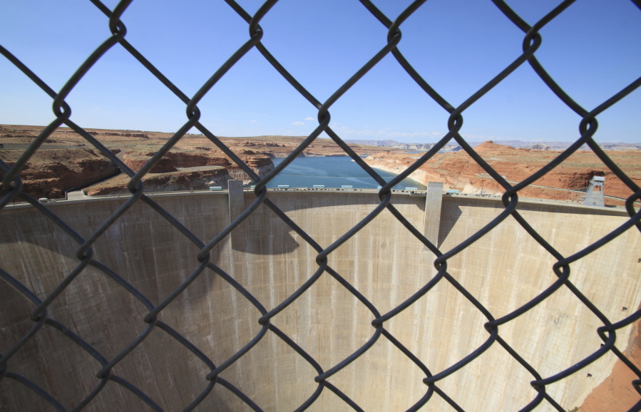 This Aug. 21, 2019 image shows Glen Canyon Dam beyond a chainlink fence near Page, Arizona. A plan by Utah could open the door to the state pursuing an expensive pipeline that critics say could further deplete the lake, which is a key indicator of the Colorado River&#039;s health.