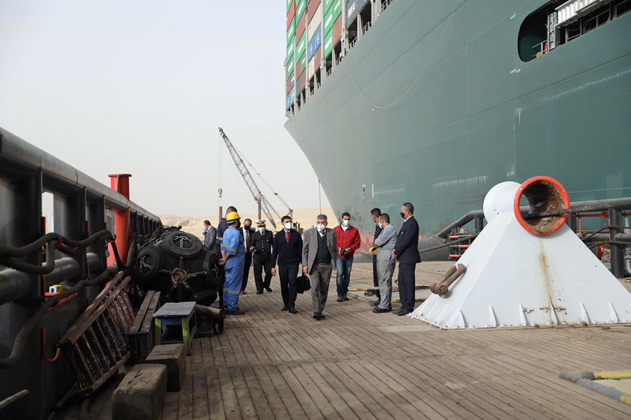 This photo released by the Suez Canal Authority on Thursday, March 25, 2021, shows Lt. Gen. Ossama Rabei, center, head of the Suez Canal Authority, with a team investigating the situation with the Ever Given, a Panama-flagged cargo ship, after it become wedged across the Suez Canal and blocking traffic in the vital waterway. An operation is underway to try to work free the ship, which further imperiled global shipping Thursday as at least 150 other vessels needing to pass through the crucial waterway idled waiting for the obstruction to clear.