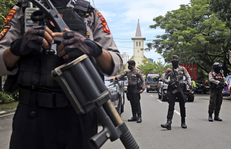 Police officers stand guard near a church where an explosion went off in Makassar, South Sulawesi, Indonesia, Sunday, March 28, 2021.
