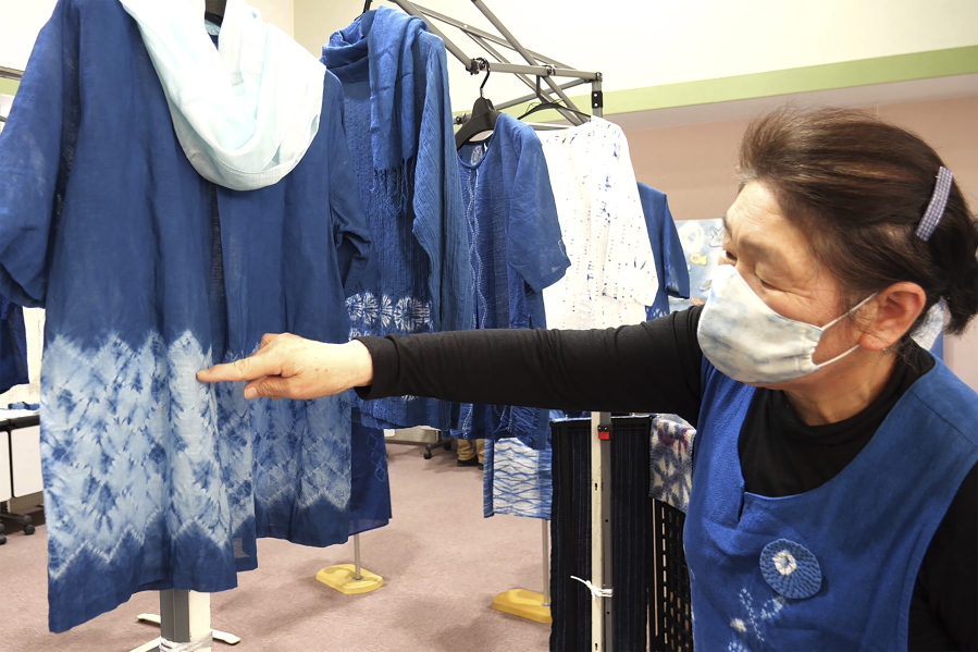 Kiyoko Mori, 65, the head of indigo dye group called Japan Blue, points out at one of displayed indigo dyed artwork Feb. 20 at a community center where residents evacuated when the 2011 earthquake hit the area in Minamisoma, Fukushima Prefecture, northeastern Japan.