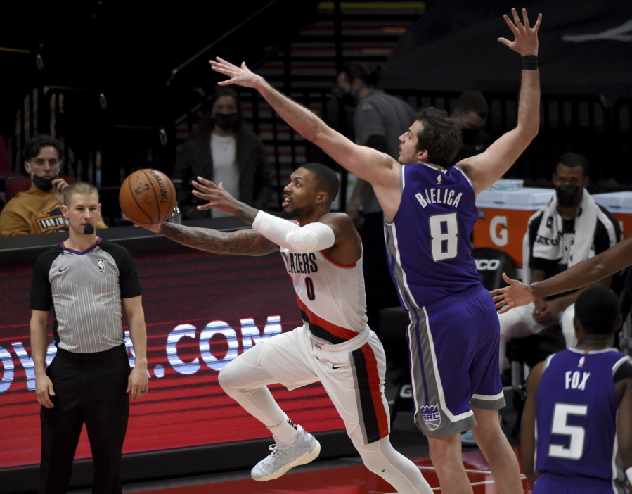 Portland Trail Blazers guard Damian Lillard, left, dives to the basket as Sacramento Kings forward Nemanja Bjelica defends during the first half of an NBA basketball game in Portland, Ore., Thursday, March 4, 2021.