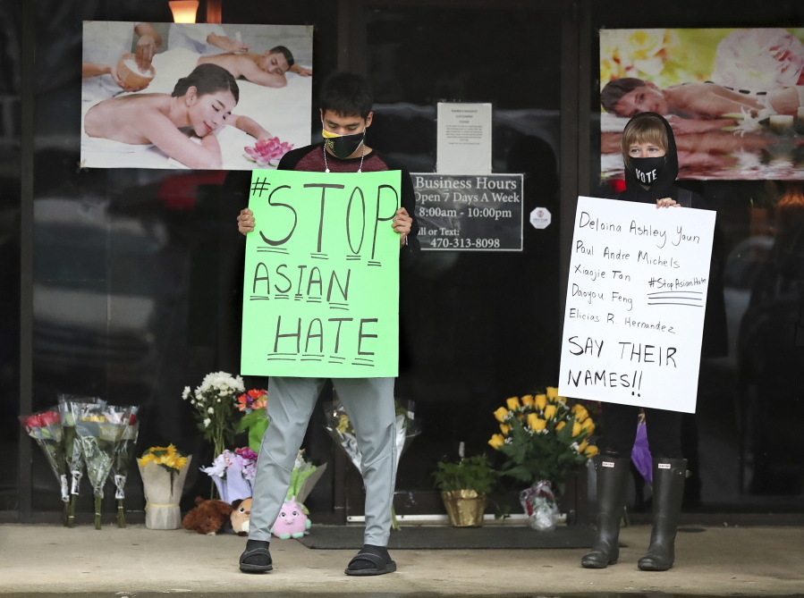 FILE - In this March 17, 2021, file photo, after dropping off flowers Jesus Estrella, left, and Shelby stand in support of the Asian and Hispanic community outside Young&#039;s Asian Massage in Acworth, Ga. The murder case against Robert Aaron Long, a white man accused of shooting and killing six women of Asian descent and two other people at Atlanta-area massage businesses, could become the first big test for Georgia&#039;s new hate crimes law.