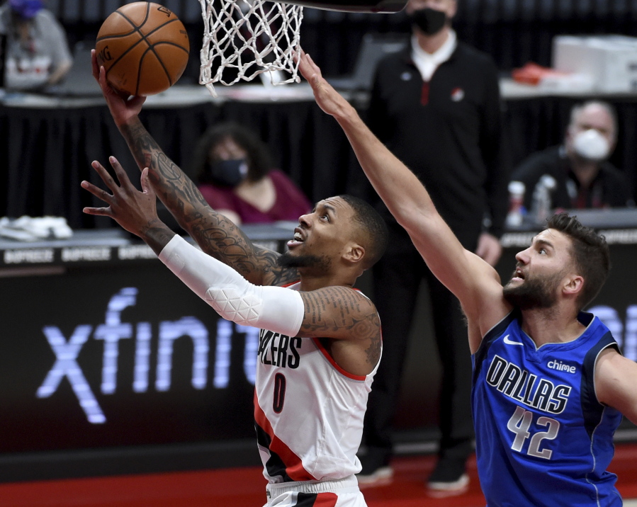 Portland Trail Blazers guard Damian Lillard, left, drives to the basket past Dallas Mavericks forward Maxi Kleber during the first half of an NBA basketball game in Portland, Ore., Friday, March 19, 2021.