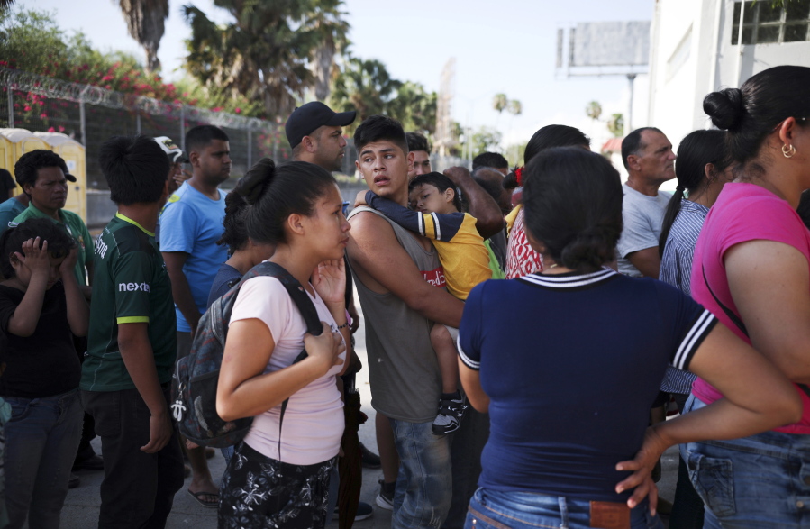 FILE - In this July 31, 2019 file photo, migrants line up in Matamoros, Mexico, for a meal donated by volunteers from the U.S., at the foot of the Puerta Mexico bridge that crosses to Brownsville, Texas. Some asylum seekers were told by officials Friday, March 5, 2021, that the U.S. government may reopen their cases and they would eventually be able to enter the U.S. to wait out the asylum process.