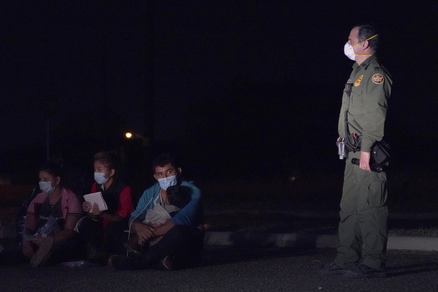 A migrant man, center, holds a child as he looks at a U.S. Customs and Border Protection agent at an intake area after crossing the U.S.-Mexico border, early Wednesday, March 24, 2021, in Roma, Texas. A surge of migrants on the Southwest border has the Biden administration on the defensive. The head of Homeland Security acknowledged the severity of the problem but insisted it&#039;s under control and said he won&#039;t revive a Trump-era practice of immediately expelling teens and children.
