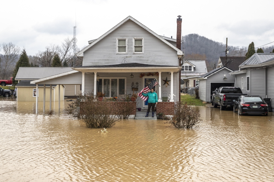 Catherine Castle stands on the porch of her home in downtown Paintsville, Ky., as floodwaters approach on Monday, March 1, 2021.  (Ryan C.