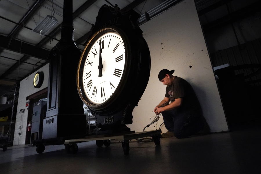 Electric Time technician Dan LaMoore lights up a two-dial Howard Post Clock, Tuesday, March 9, 2021, in Medfield, Mass. Daylight saving time begins at 2 a.m. local time Sunday, March 14, 2021, when clocks are set ahead one hour.