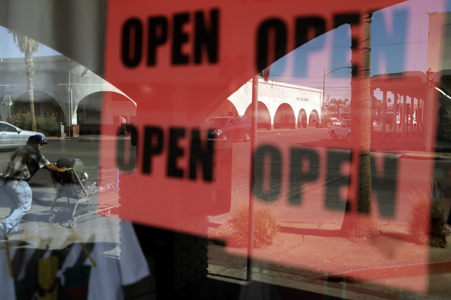 ADVANCE FOR RELEASE MARCH 14, 2021, AND THEREAFTER - FILE - In this June 30, 2020, photo, a man passes a clothing shop with open signs in the window in Calexico, Calif. A year after the first coronavirus shutdowns, many U.S. states and cities are still struggling with a silent side effect: Public records have become harder to get. As states prepared to reopen their economies following coronavirus shutdowns last spring, The Associated Press asked governors across the U.S. for records that could shed light on how businesses and health officials influenced their decisions.
