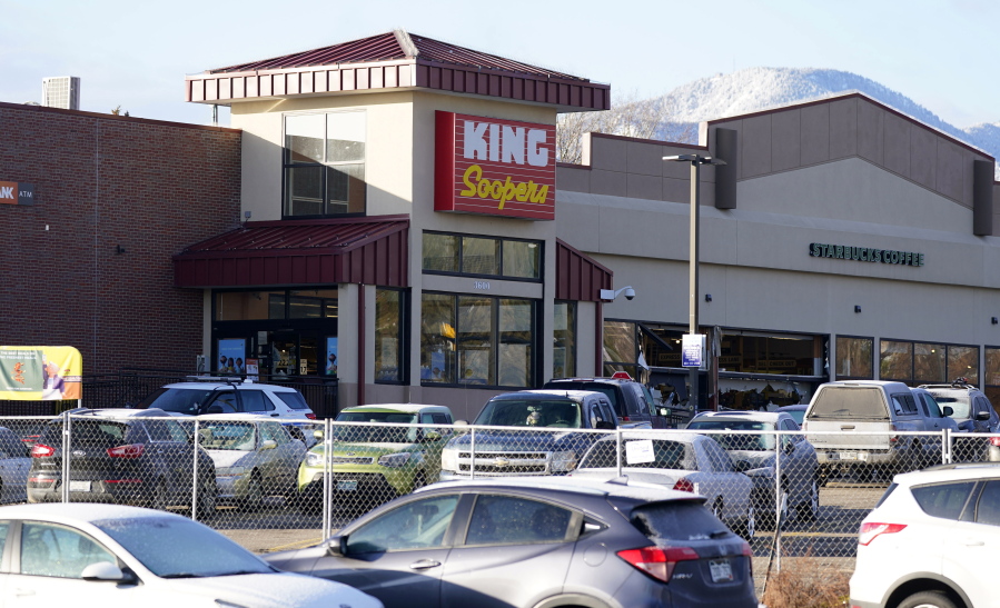 In this March 23, 2021, photo, a makeshift fence stands around the parking lot outside a King Soopers grocery store where a mass shooting took place in Boulder, Colo. The suspects in the most recent shooting sprees found it relatively easy to get their guns. The suspect in the shooting at a Boulder supermarket was convicted of assaulting a high school classmate but still got a gun.