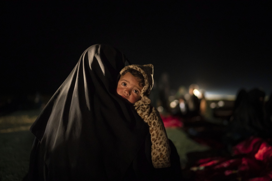FILE - In this Feb. 25, 2019 file photo, a woman carries her baby at a screening center run by U.S.-backed Syrian Democratic Forces after being evacuated out of the last territory held by Islamic State militants, outside Baghouz, Syria. Hundreds of thousands of Syrians face continued displacement each coming year if the conflict continues and economic conditions further deteriorate, the Norwegian Refugee Council, a prominent humanitarian organization said Monday, March 8, 2021. The Syrian conflict, which marks 10 years later this month, has resulted in the largest displacement crisis since World War II, the council said.