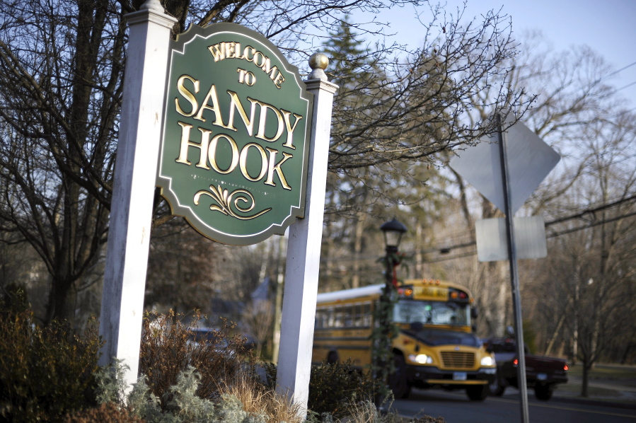 FILE - In this Dec. 4, 2013, file photo, a school bus drives past a sign reading Welcome to Sandy Hook, in Newtown, Conn., where 26 people were killed by a gunman inside Sandy Hook Elementary School. Students who were planning to attack schools showed the same types of troubled histories as those who carried them out - they were badly bullied, often suffered from depression with stress at home, and their behavior worried others, according to a U.S.