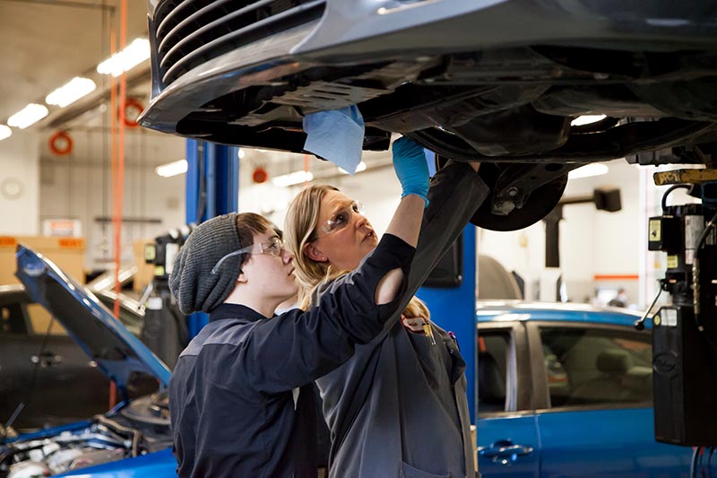 Clark College automotive technology professor Tonia Haney prepares a student for removing a vehicle’s engine during a lab class.