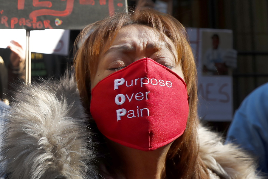 A member of St. Sabina Catholic Church wears a face mask in support of Father Michael Plfeger as she takes part in a rally outside the Archdiocesan Pastoral Center in Chicago demanding resolution of the investigation into allegations against Pfleger Wednesday, Feb. 10, 2021, in Chicago.