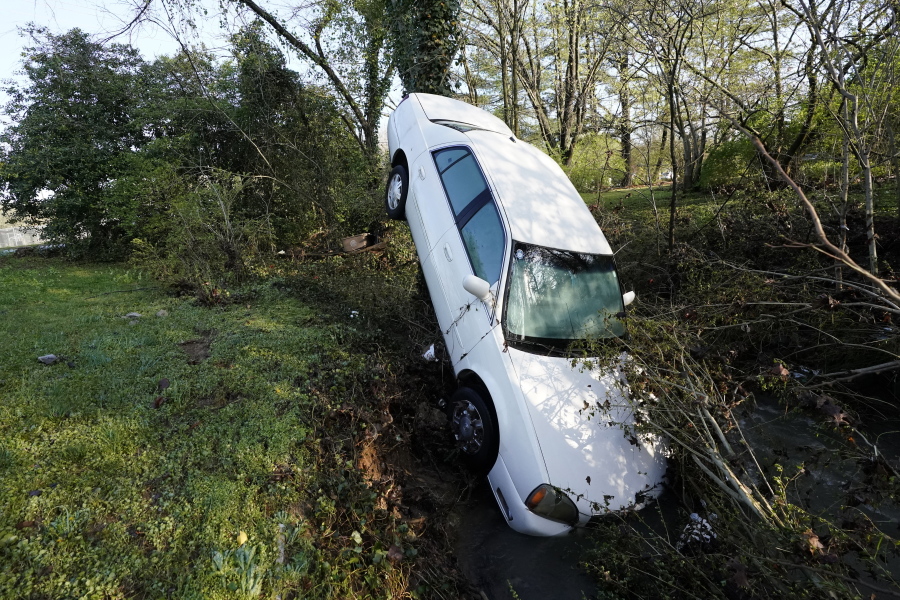 A car that was carried by floodwaters leans against a tree in a creek Sunday, March 28, 2021, in Nashville, Tenn. Heavy rain across Tennessee flooded homes and roads as a line of severe storms crossed the state.