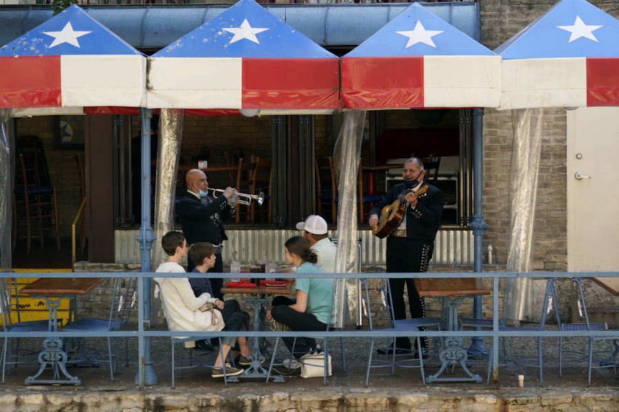 FILE - In this March 3, 2021, file photo, mariachi perform for diners at a restaurant on the River Walk in San Antonio. U.S. employers added a surprisingly robust 379,000 jobs in February in a sign the economy is strengthening as virus cases drop, vaccinations ramp up, Americans spend more and states ease business restrictions. Texas joined some other states in announcing it will fully reopen its economy.