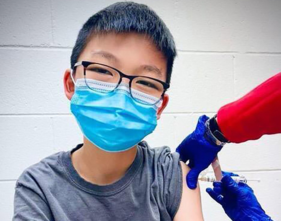 In this Dec. 22, 2020, photo, provided by Richard Chung, his son Caleb Chung receives the first dose of Pfizer coronavirus vaccine or placebo as a trial participant for kids ages 12-15, at Duke University Health System in Durham, N.C. Pfizer says its COVID-19 vaccine is safe and strongly protective in kids as young as 12. The announcement Wednesday, March 31, 2021 marks a step toward possibly beginning shots in this age group before the next school year.