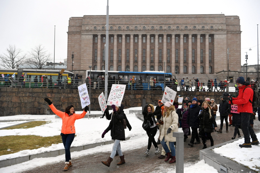 A group of people hold placards during a protest against the Finnish government&#039;s regulations to fight the coronavirus pandemic in Helsinki, Saturday, March 20, 2021. Some 400 protesters gathered peacefully in downtown Helsinki.