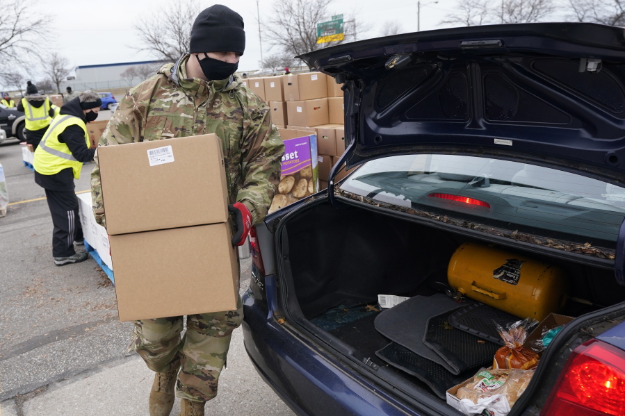 Staff Sgt. Mike Schuster loads two produce boxes into a car at a food bank distribution by the Greater Cleveland Food Bank, Thursday, Jan. 7, 2021, in Cleveland.