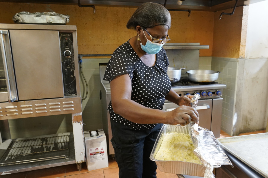 Doramise Moreau covers shredded malanga that will be served with baked fish to those that need a meal at Notre Dame d&#039;Haiti Catholic Church, Monday, March 8, 2021, in Miami. Moreau is a part-time janitor at a technical school. She spends most of her time shopping for ingredients and helping to cook meals for 1,000 to 1,500 people a week since the pandemic began. Moreau received a new car for her community service. She was nominated by the pastor at the church.
