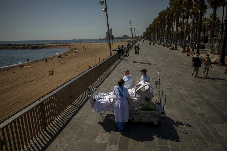 FILE - In this Sept. 4, 2020, file photo, Francisco Espana, 60, is surrounded by members of his medical team as he looks at the Mediterranean sea from a promenade next to the &quot;Hospital del Mar&quot; in Barcelona, Spain. Francisco spent 52 days in the Intensive Care unit at the hospital due to coronavirus, but today he was allowed by his doctors to spend almost ten minutes at the seaside as part of his recovery therapy.