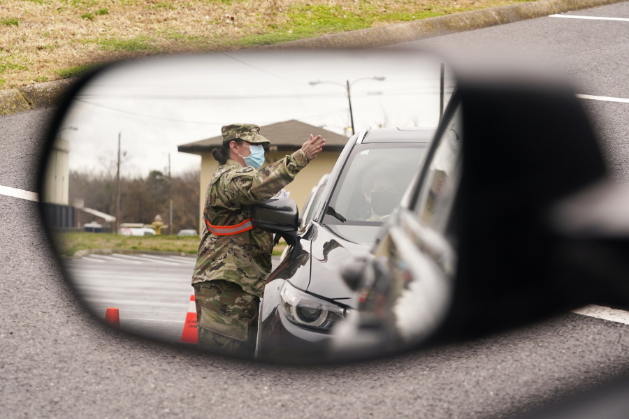 A National Guard soldier directing drivers is reflected in the mirror of a car waiting in a COVID-19 vaccination line Feb. 26, 2021, in Shelbyville, Tenn. Tennessee has continued to divvy up vaccine doses based primarily on how many people live in each county, and not on how many residents belong to eligible groups within those counties.
