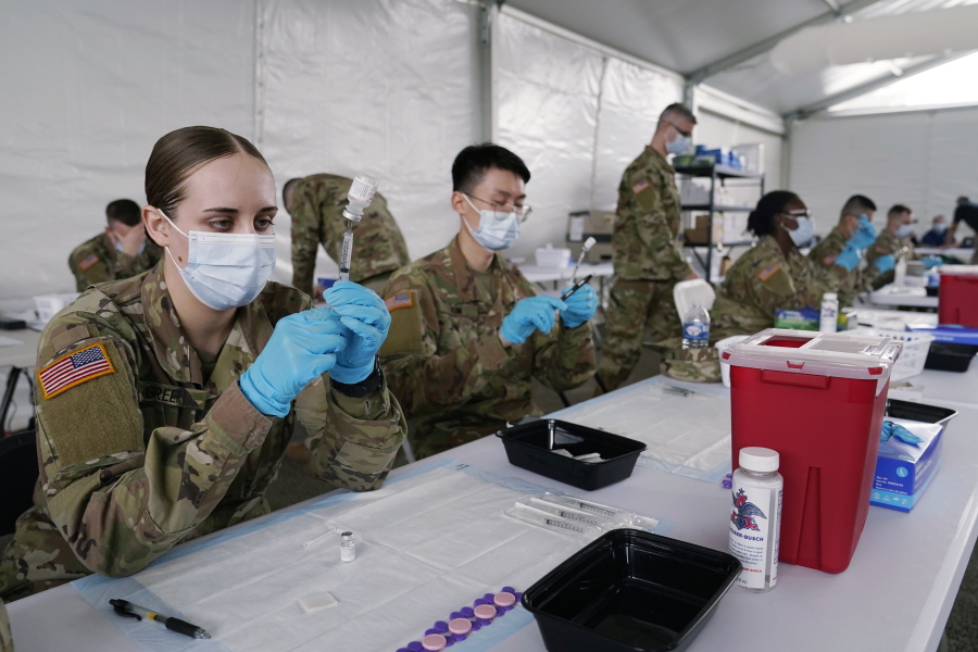 FILE - In this March 9, 2021, file photo, Army health specialists fill syringes with the Pfizer COVID-19 vaccine in Miami. Despite the clamor to speed up the U.S. vaccination drive against COVID-19, the first three months of the rollout suggest faster is not necessarily better.