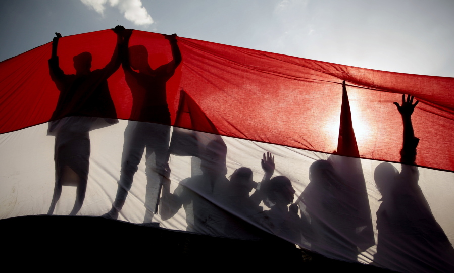 FILE - In this Sept. 26, 2016 file photo, men are silhouetted against a large representation of the Yemeni flag as they attend a ceremony to mark the anniversary of North Yemen&#039;s 1962 revolution in Sanaa, Yemen. On Monday, March 22, 2021, Saudi Arabia announced a plan to to offer Yemen&#039;s Houthi rebels a cease-fire in the country&#039;s yearslong war and allow a major airport to reopen in its capital. The Houthis offered no immediate comment to the proposal.