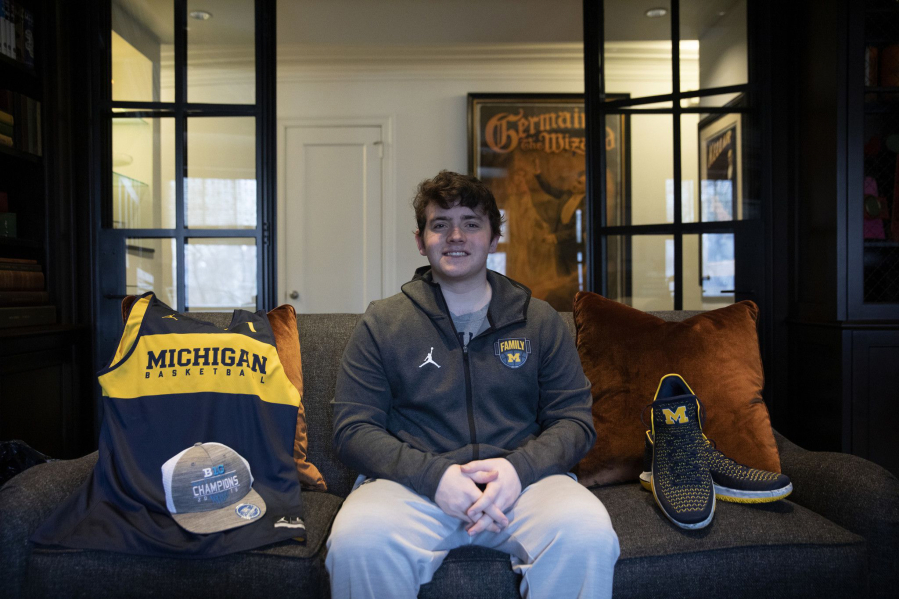 Jason Lansing, 22, a University of Michigan senior from Chicago, sits with some of his Michigan gear for his online business selling game-worn sports gear in partnership with former college athletes on March 25, 2021, in Chicago. The Players Trunk, which stores merchandise in a suburban family garage, is growing so fast it was recently funded by a Chicago venture capital firm.