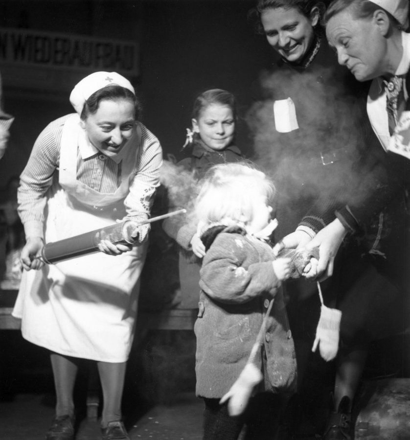 October 1945:  A child crying as she is sprayed with DDT delousing powder at Nikolsburger Platz School, Wilmsdorf, Germany.