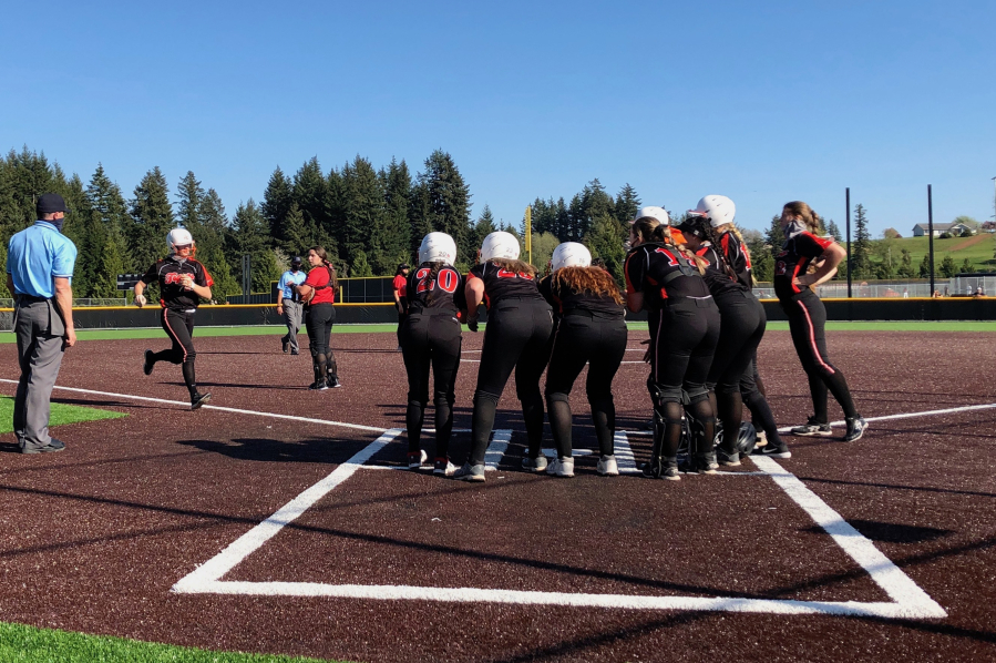 Battle Ground softball players greet Candice Adams at home plate after she hit a grand slam in the Tigers' 17-4 win over Camas on Wednesday at Camas High School (Micah Rice/The Columbian).