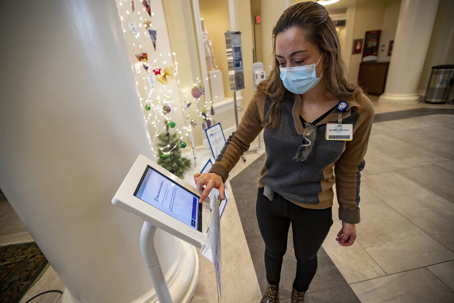 Interpreter Ana Maria Rios-Velez demonstrates the screening app at the front entrance of Brigham and Women's Hospital in Boston. It has a multilingual function to better communicate with non-English-speaking patients and staffers.