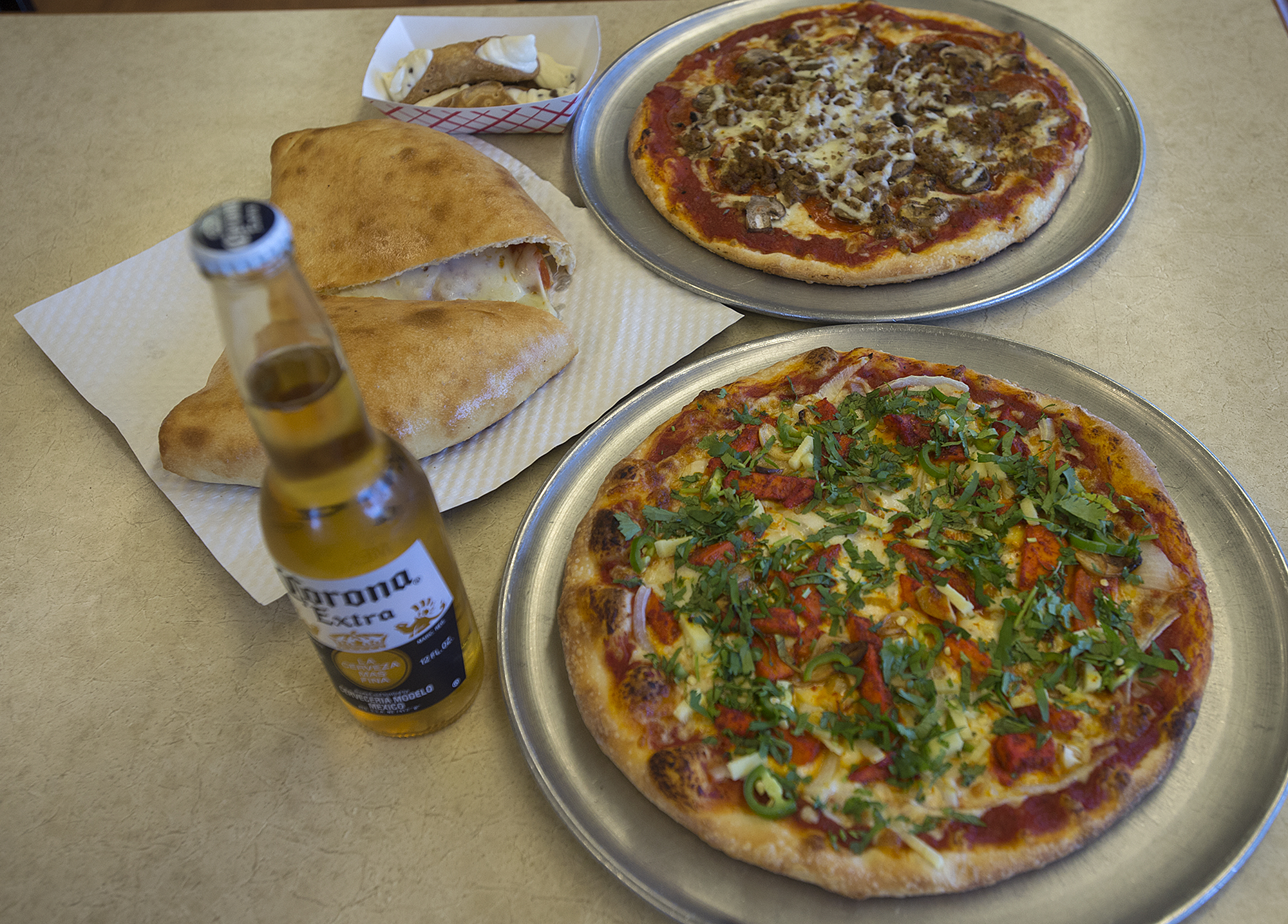 The Punjabi special, clockwise from bottom, a calzone with pepperoni and a NYC pizza is pictured at N.Y.C. Pizzeria on Friday afternoon, April 26, 2019.