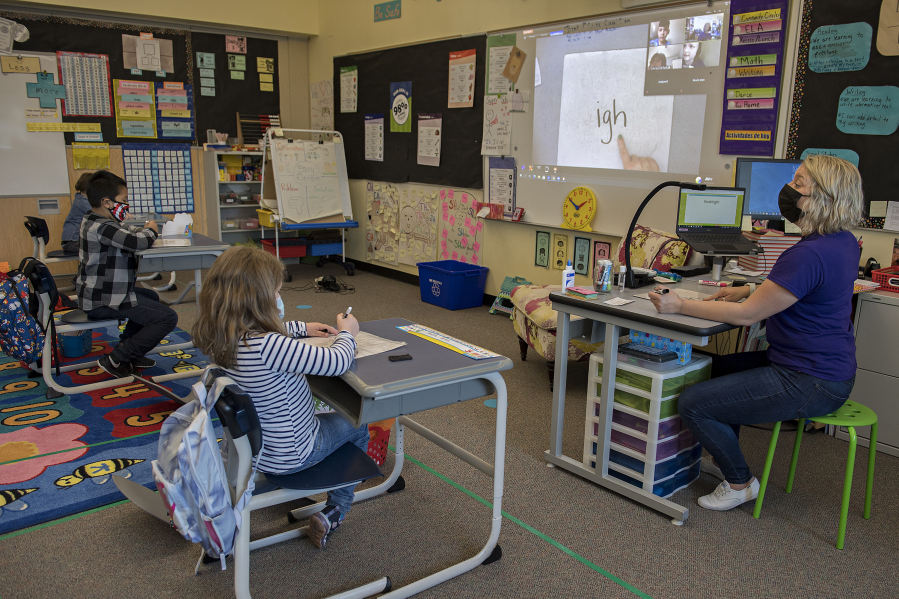 First-graders Jared Perez Bello, 7, from left, and Amelia Perkins, 6, take part in a lesson as classmates at home join remotely with teacher Tiffany Martinson at Washington Elementary School in Vancouver. When Clark County school districts transitioned to hybrid instruction in January, for many teachers, it included teaching simultaneously to two sets of students: in-person and virtually through Zoom. Now, Clark County districts are making another change after new state guidance allows for more spacing in classrooms between students.