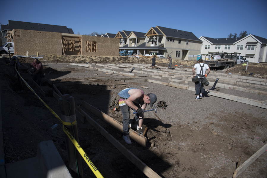Russell Hines of Brothers Concrete Inc., foreground, helps to build a triplex at the 2 Creeks development in Camas on Wednesday. Clark County's housing market is facing a record low supply, and industry professionals say it's not that new listings have dried up or the pace of building has slowed down - it's just that there's no way to keep up with the current level of demand.