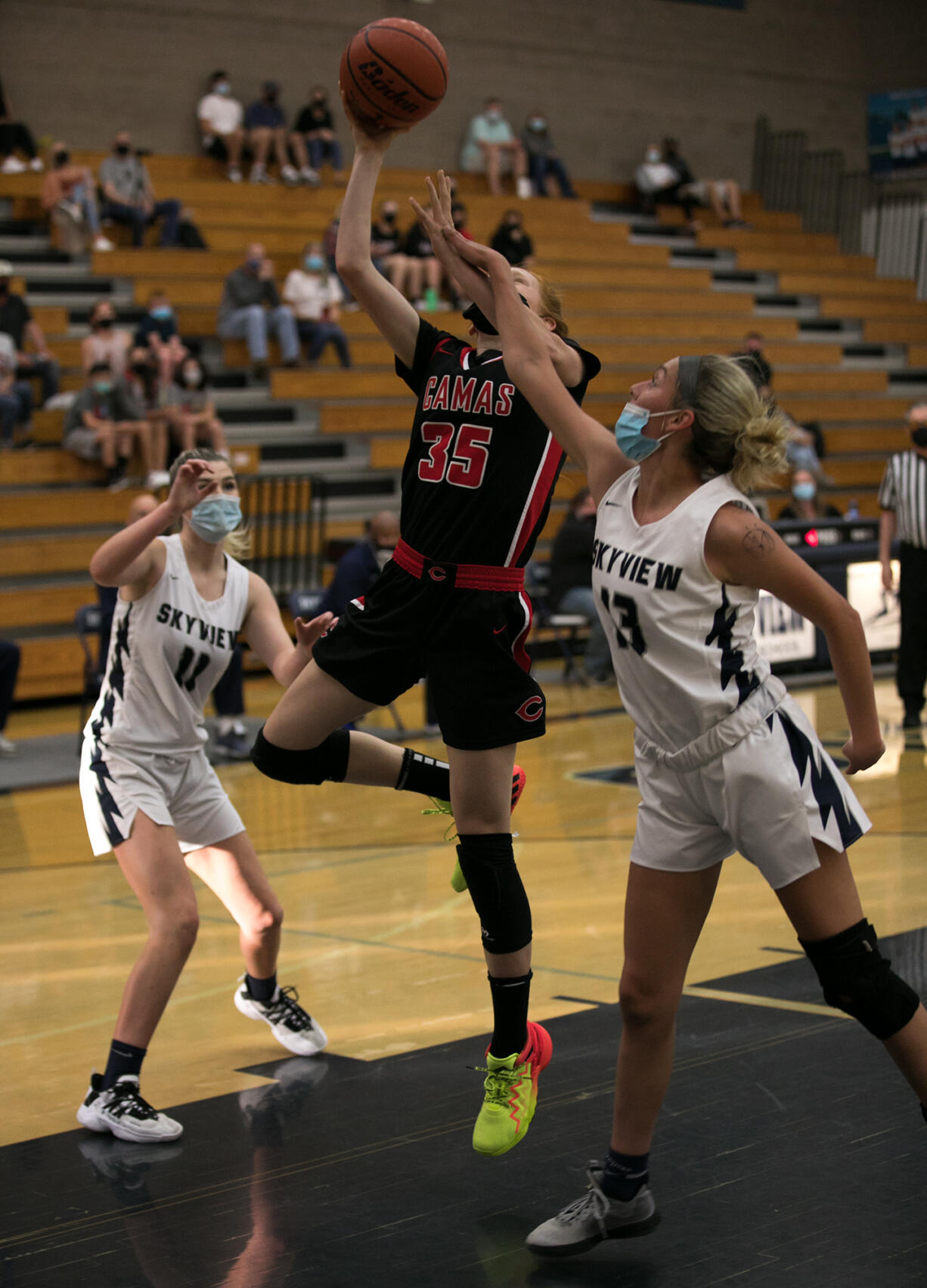 Camas' Addison Harris (35) attempts a lay-up while being defended by Skyview 's Avery Wilson (11) and Skylar Groesbeck (13) during the first half at Skyview High School on Thursday, April 29, 2021.