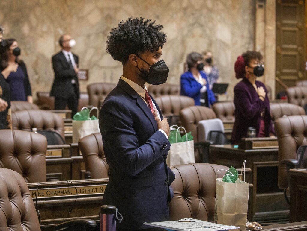 FILE - In this Jan. 11, 2021, file photo, Rep. Jesse Johnson, D-Federal Way, stands with other members at the beginning of the House session, where legislators were spaced at a social distance, in Olympia, Wash. Johnson hopes to see the Legislature end qualified immunity for police officers, which would allow them to be sued in state court, and to see it authorize community oversight boards that could have input on local policies and receive complaints about officers.