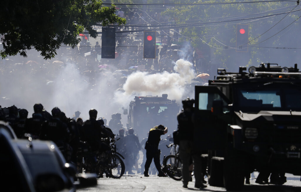 FILE - In this July 25, 2020, file photo, smoke rises as police clash with protester during a Black Lives Matter protest near the Seattle Police East Precinct headquarters in Seattle. Mayors, county executives or even the governor would have to give their approval before police could use tear gas to quell riots under a compromise reached in the Washington Legislature. A conference committee of the House and Senate met Thursday, April 22, 2021, to reconcile versions of a police tactics bill already approved by each chamber. (AP Photo/Ted S.
